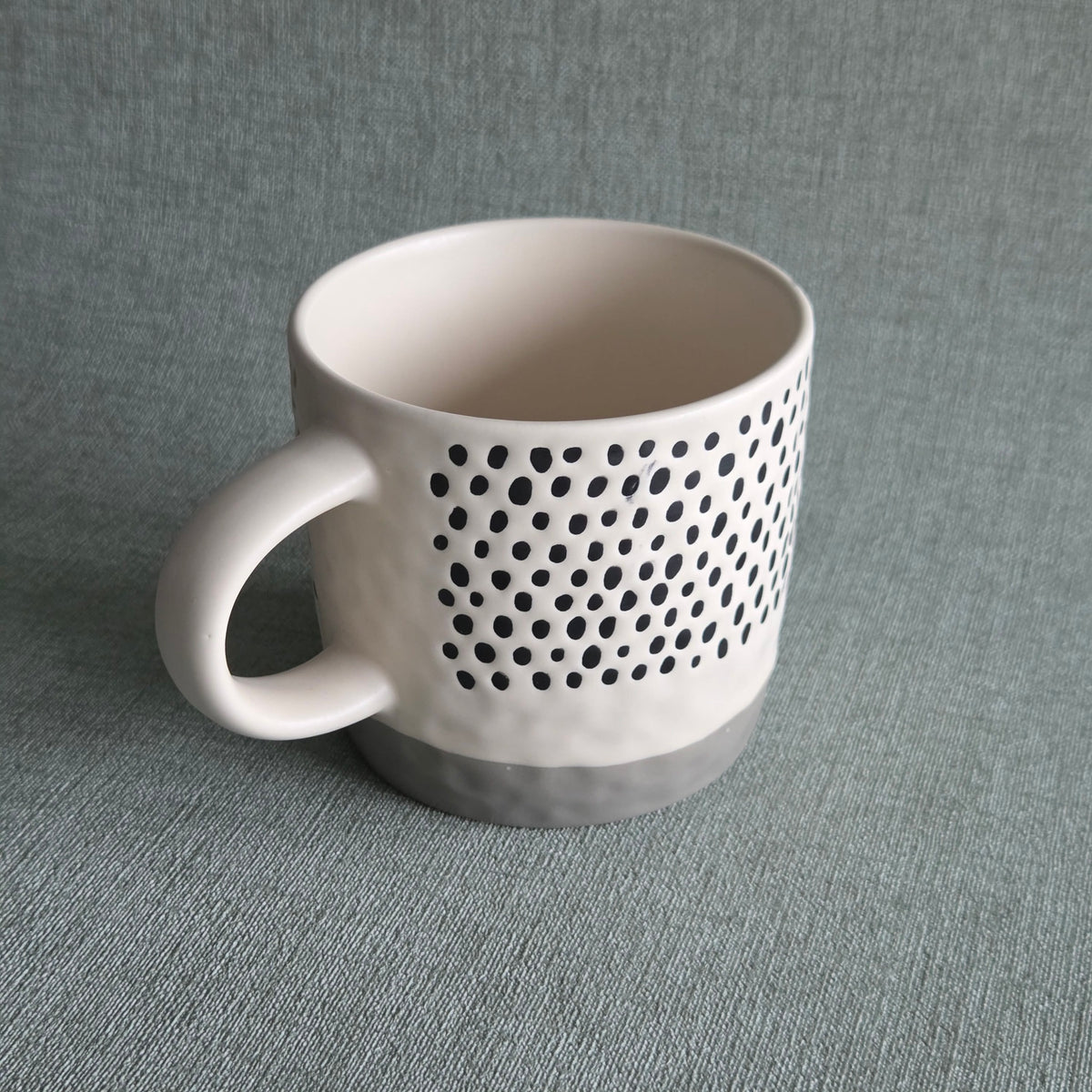 Witte keramische mok met zwart stippenpatroon en grijze voet, productfoto van Mok Reva Stone
