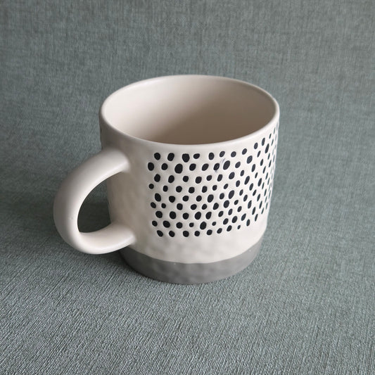 Witte keramische mok met zwart stippenpatroon en grijze voet, productfoto van Mok Reva Stone
